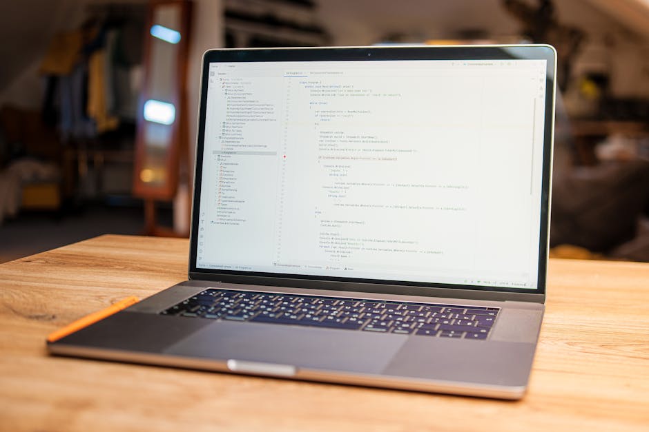 A close-up of an open laptop placed on a wooden desk, displaying lines of code on its screen, with a blurred background of a cozy, well-lit indoor space featuring wooden furniture and soft lighting, s
